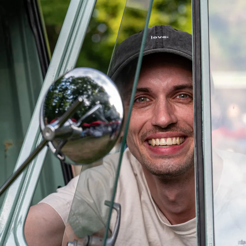Joshua, Co-Founder von apeice, lacht aus dem Fenster der Ape